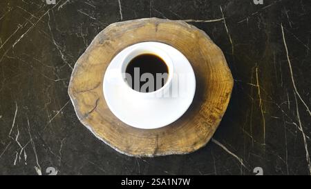 Vue aérienne d'une tasse de café sur un dessous de verre en bois sur une table en marbre sombre, Istanbul, TURQUIE Banque D'Images