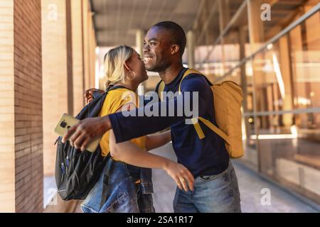 Étudiants multiraciaux souriant heureux tout en embrassant et saluant sur le campus universitaire Banque D'Images