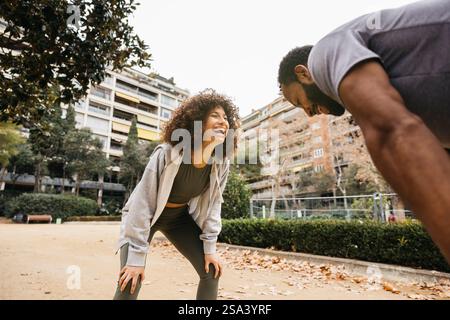 Deux personnes participent avec plaisir à une séance de fitness dans un parc urbain extérieur, mettant en valeur l'énergie, la motivation et la camaraderie pendant leur worko Banque D'Images