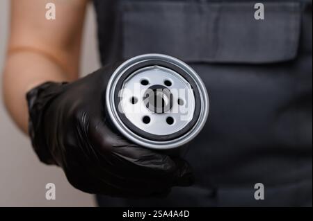 Mécanicien automatique dans les gants tient le filtre à carburant en métal pour les voitures diesel, gros plan. Entretien et réparation de voiture professionnelle technique, remplacement opportun de fu Banque D'Images