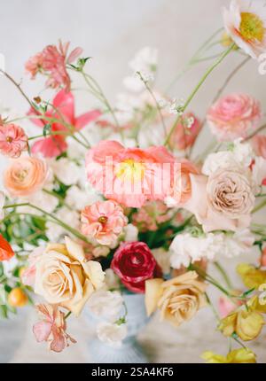 Un beau bouquet rempli de fleurs variées, y compris des roses roses roses et des ranoncules, élégamment disposés dans un vase vintage. Lumière douce et naturelle Banque D'Images