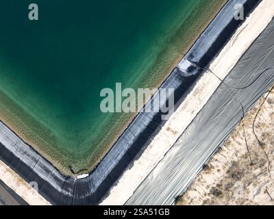 Vue aérienne abstraite d'un étang de rétention d'eau carrée de couleur aqua utilisé pour la fracturation hydraulique dans l'ouest du Texas Banque D'Images