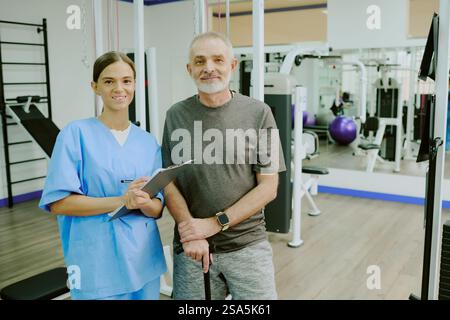 Portrait moyen en gros plan d'un patient âgé posant pour la photo avec son jeune physiothérapeute professionnel Banque D'Images