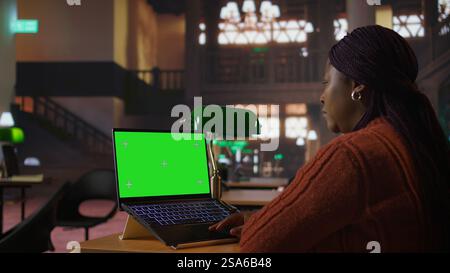 Bibliothécaire afro-américain travaillant avec des ressources académiques à côté de l'espace de copie, gérant le matériel d'apprentissage dans la base de données de la bibliothèque publique. Femme tutrice concentrée sur sa profession. Caméra A. Banque D'Images