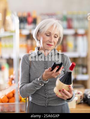Femme âgée scannant le code qr du vin Banque D'Images