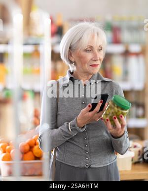 Femme âgée scannant le code qr pour les olives Banque D'Images