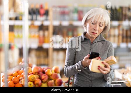 Femme âgée scannant le code qr pour le fromage Banque D'Images