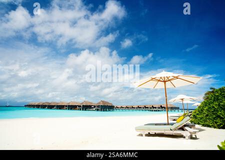 Des chaises longues en bois sur une belle plage tropicale à Maldives Banque D'Images