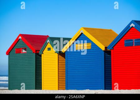 Rangée de boîtes à langer de style victorien bleu, jaune, rouge et vert distinctif sur pilotis le long du célèbre littoral sablonneux de Muizenberg Banque D'Images