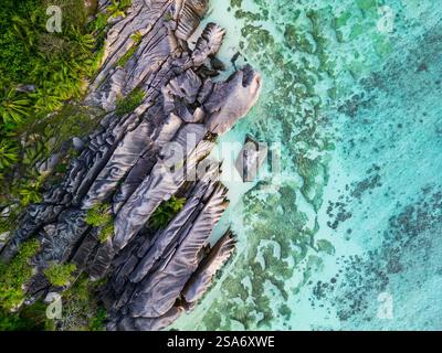 Vue aérienne de la Digue, aux Seychelles, avec des formations rocheuses granitiques saisissantes le long du littoral luxuriant, se mélangeant parfaitement à l'eau turquoise Banque D'Images