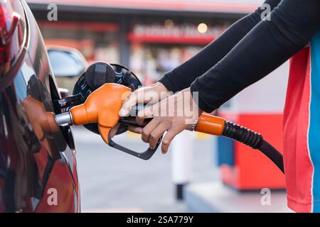 Ravitaillement de la voiture à la pompe à essence d'une station-service. Homme conducteur main de remplissage et de pompage d'huile d'essence la voiture avec du carburant à la station de ravitaillement. Recharge pour mains Banque D'Images