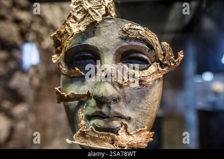 Un visage avec des feuilles d'or dessus. Le visage est fait de bronze et a des feuilles d'or sur elle Banque D'Images