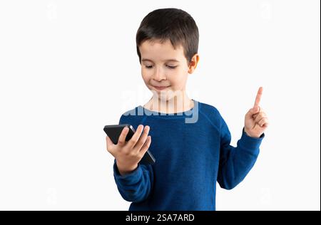 SMS enfant à l'aide d'un smartphone sur fond isolé très heureux pointant la main et le doigt sur le côté Banque D'Images