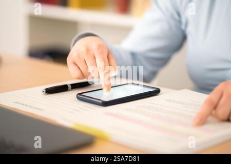 Gros plan des mains d'entrepreneur signant contrat sur téléphone intelligent avec le doigt à la maison Banque D'Images
