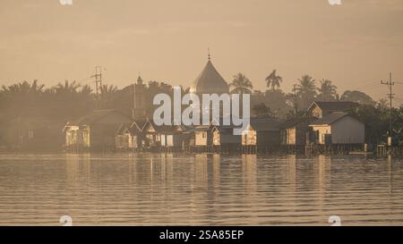 Serein Riverside Village au lever du soleil avec le dôme de la mosquée et les maisons traditionnelles reflétant dans la rivière Martapura Banque D'Images