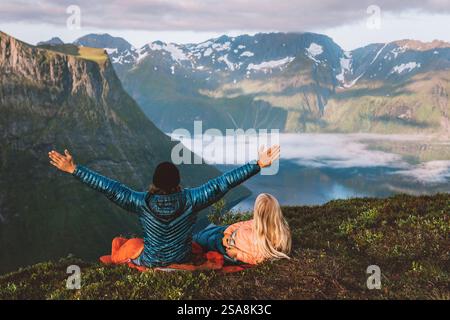 Couple dans des sacs de couchage sur un bivouac dans les montagnes de Norvège, homme heureux leva la main. Amis randonnée avec matériel de camping, profiter de vacances romantiques actif Banque D'Images