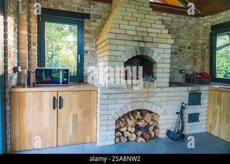 Cheminée en briques dans une cuisine de campagne, entourée de bois naturel et d'un décor rustique. Banque D'Images