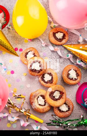 Carnaval sucre en poudre beignets élevés avec gelée et fromage à la crème, banderoles en papier et confettis Banque D'Images