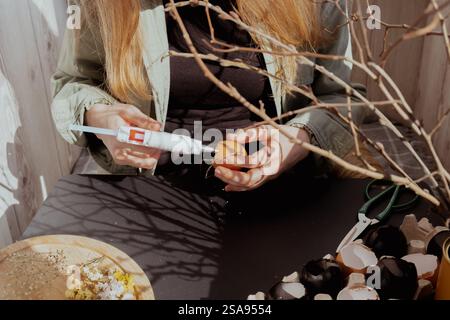 Femme méconnaissable créant une décoration de vacances de Pâques à partir de coquille d'œuf. DIY faites-le vous-même étape par étape instruction. Vacances de préparation artisanale Banque D'Images