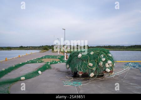 Filets de pêche sur le quai du port. Tas de filets de pêche au chalut colorés et de flotteurs sur le quai du port. Soirée d'été au bord de la mer. Banque D'Images