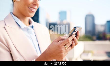 Femme professionnelle utilisant smartphone à l'extérieur dans un cadre urbain de ville Banque D'Images