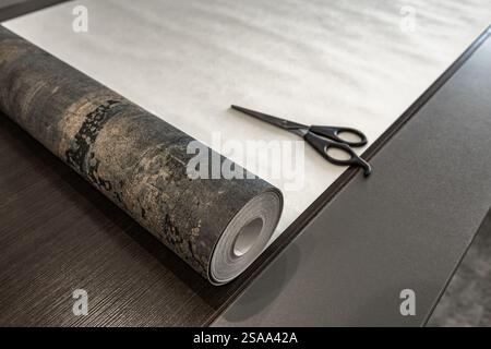 Couper le papier peint avant de le coller au mur, ciseaux, ruban à mesurer et crayon sur la table, couper le papier peint à la taille Banque D'Images