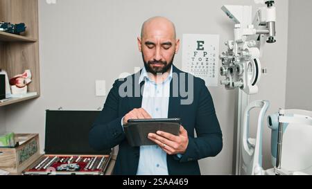 Optométriste professionnel utilisant la tablette dans le bureau moderne avec l'équipement médical Banque D'Images