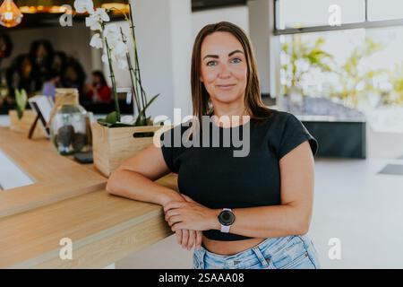 Une femme se tient debout devant un comptoir avec une montre au poignet. Elle sourit et elle est heureuse Banque D'Images