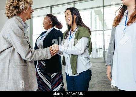 Des femmes professionnelles se rencontrent et se serrent la main, favorisant les connexions et la collaboration lors d'un événement d'entreprise Banque D'Images