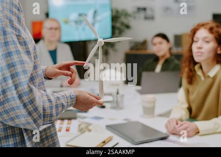 Vue rapprochée d'une personne tenant un modèle d'éolienne tout en présentant l'énergie durable à un groupe diversifié dans un environnement de bureau pendant la session de réunion Banque D'Images