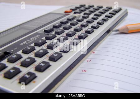 Ordinateur de banque de données vintage dispositif clavier qwerty et un crayon. Ancienne banque de données d'ordinateur de poche sur un bloc-notes avec un stylo affûté au plomb graphite Banque D'Images