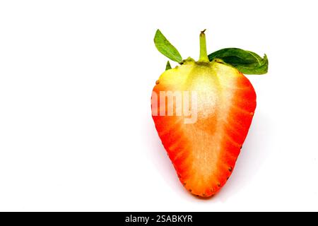 Vue rapprochée d'une fraise fraîche coupée en moitié isolée sur un fond blanc Uni Banque D'Images