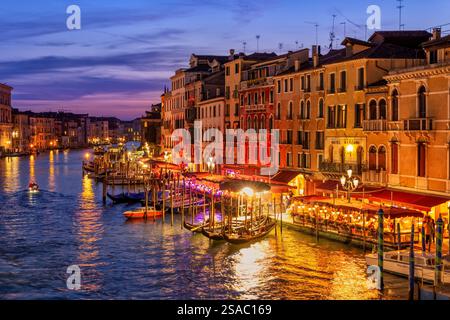 Soirée dans le centre-ville de Venise en Italie. Le Grand canal vu depuis le pont du Rialto, bordé de manoirs historiques, de restaurants et de gondoles. Banque D'Images