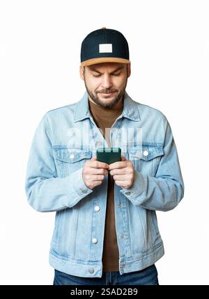 Découpe d'un jeune homme adulte avec une barbe courte portant une veste en Jean et casquette snapback texturée sur smartphone. Banque D'Images