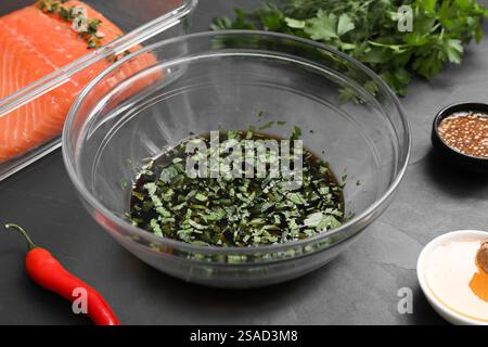 Marinade de soja dans un bol, filet de saumon et autres produits sur une table texturée gris foncé, gros plan Banque D'Images