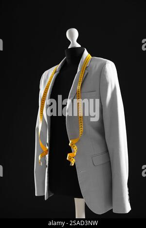 Mannequin féminin avec veste grise et ruban à mesurer sur fond sombre Banque D'Images