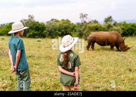 Vue arrière d'enfants sur safari à pied près de white rhino Banque D'Images