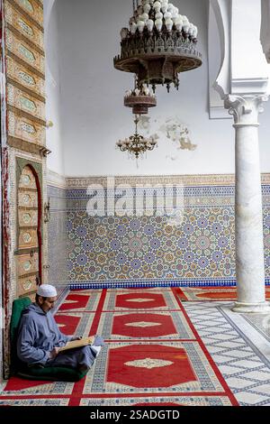 Fidèle assis et lisant Kuran dans le mausolée Moulay Driss i, (Maqam Moulay Idriss), Moulay Idriss Zerhoun, Maroc Banque D'Images