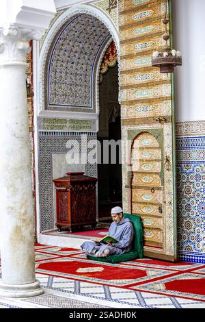 Fidèle assis et lisant Kuran dans le mausolée Moulay Driss i, (Maqam Moulay Idriss), Moulay Idriss Zerhoun, Maroc Banque D'Images