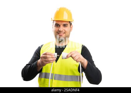 Ouvrier de construction masculin amical portant un gilet fluorescent et un cordon d'extension de prise de connexion de casque de sécurité jaune isolé sur fond blanc Banque D'Images