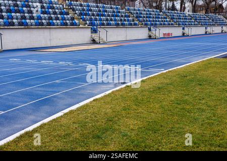 Pistes de course bleues avec numéros. Sièges rabattables en plastique au stade de la ville. Sièges bleus et gris dans les tribunes. Banque D'Images