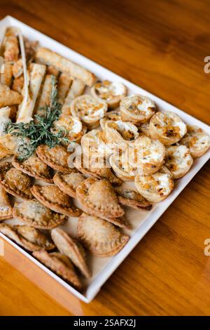 Une sélection alléchante de pâtisseries salées et d'en-cas est bien en vue sur une table en bois, idéale pour une réunion festive entre amis ou entre amis Banque D'Images