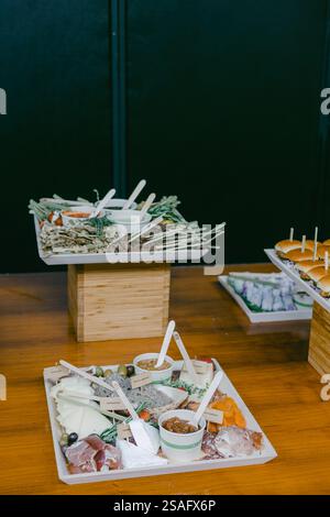Un présentoir magnifiquement agencé présente une variété d'entrées, de garnitures et de sauces servies sur des stands en bois, idéal pour une réunion ou un événement social. Banque D'Images