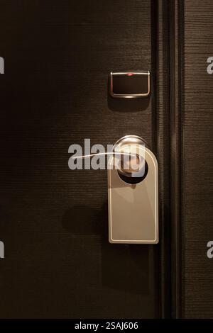 Etiquette vide dans le panneau « ne pas déranger » accroché à l'élégante porte de la chambre d'hôtel Banque D'Images