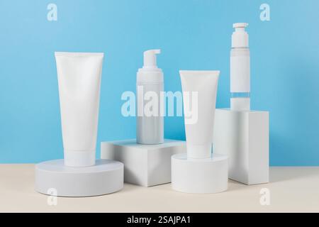 Beaux modèles cosmétiques pour les annonces, tubes de crème en plastique et bouteilles sur un fond bleu avec des podiums. Design esthétique pour un produit haut de gamme Banque D'Images