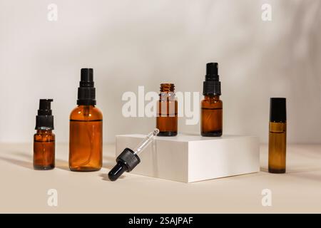 Bouteilles en verre ambré utilisées pour les soins de la peau ou les produits cosmétiques. disposés sur des plates-formes blanches sur un fond beige clair. Souvent associé à essent Banque D'Images