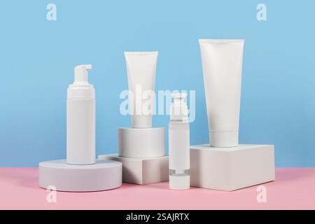 Beaux modèles cosmétiques pour les annonces, tubes de crème en plastique et bouteilles sur un fond bleu avec des podiums. Design esthétique pour un produit haut de gamme Banque D'Images