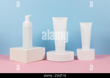 Beaux modèles cosmétiques pour les annonces, tubes de crème en plastique et bouteilles sur un fond bleu avec des podiums. Design esthétique pour un produit haut de gamme Banque D'Images