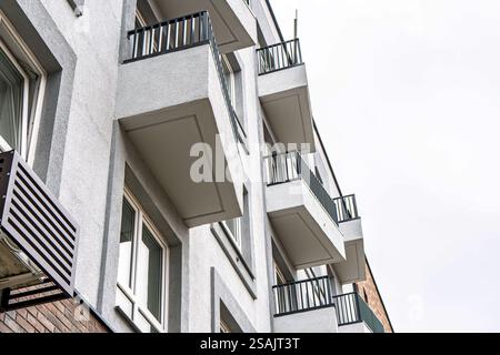 Bâtiment moderne avec plusieurs balcons avec des garde-corps en métal, avec un fond de ciel nuageux, concept d'architecture urbaine, vue en angle bas Banque D'Images