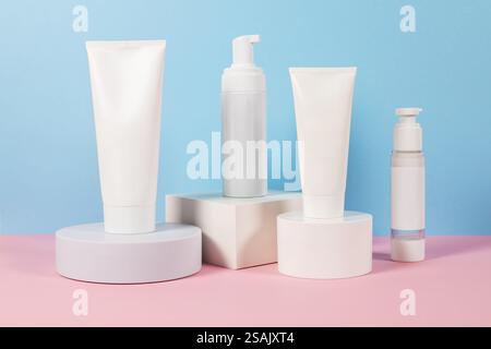 Beaux modèles cosmétiques pour les annonces, tubes de crème en plastique et bouteilles sur un fond bleu avec des podiums. Design esthétique pour un produit haut de gamme Banque D'Images
